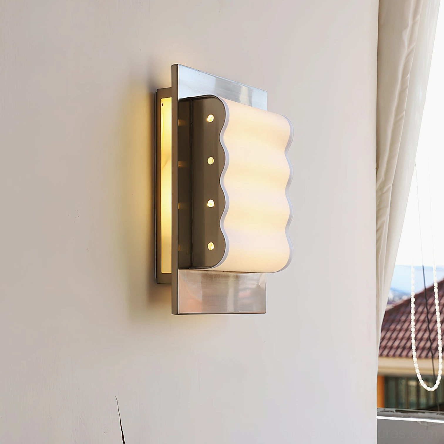 Modern ripple edge wall sconce mounted in residential interior with silver finish and warm diffused lighting