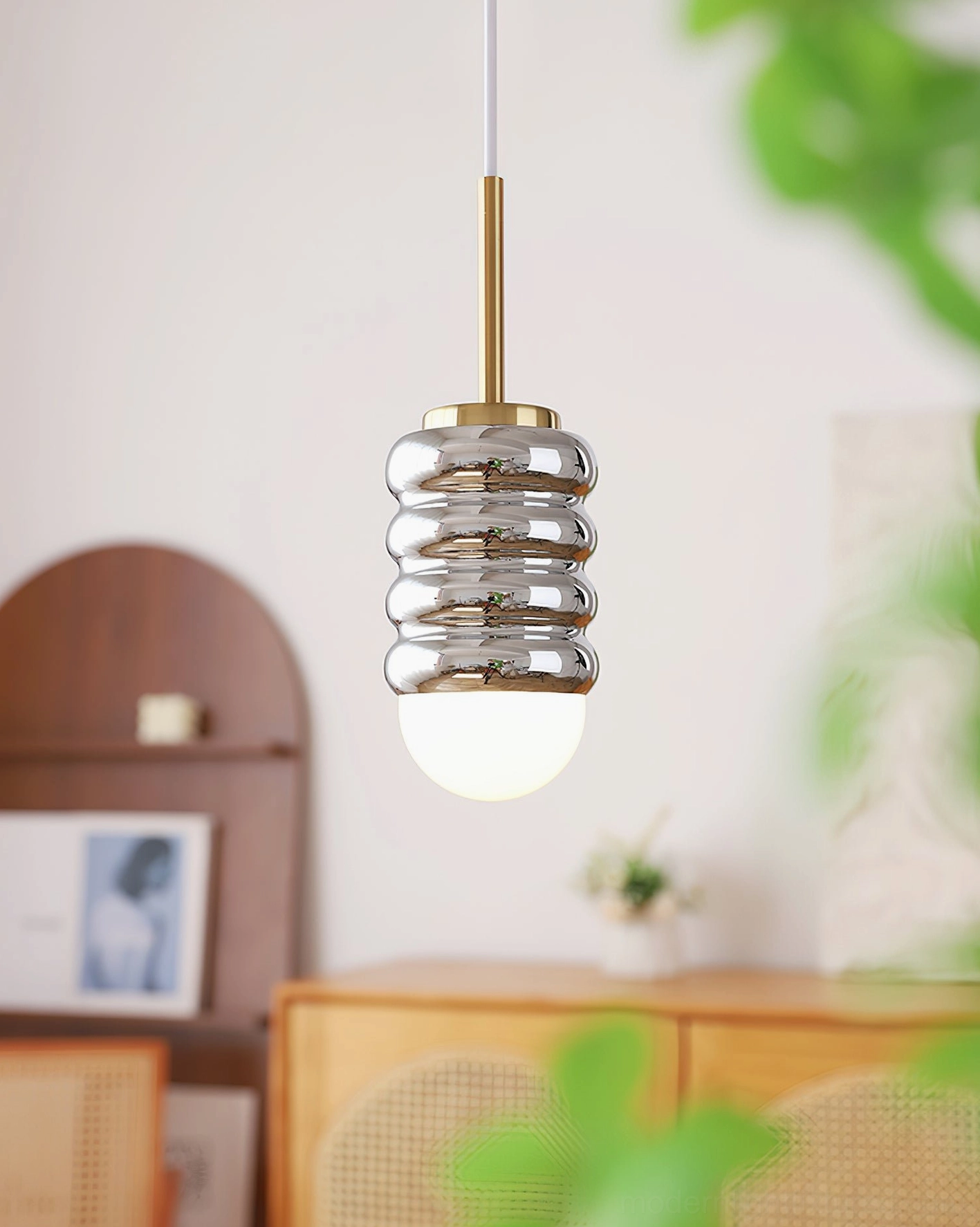 Modern hanging light with silver mirrored corrugated shade and brass gold hardware in vintage interior setting