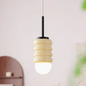 Modern ceramic pendant light in cream with black metal top, displayed in vintage bedroom setting with warm glow