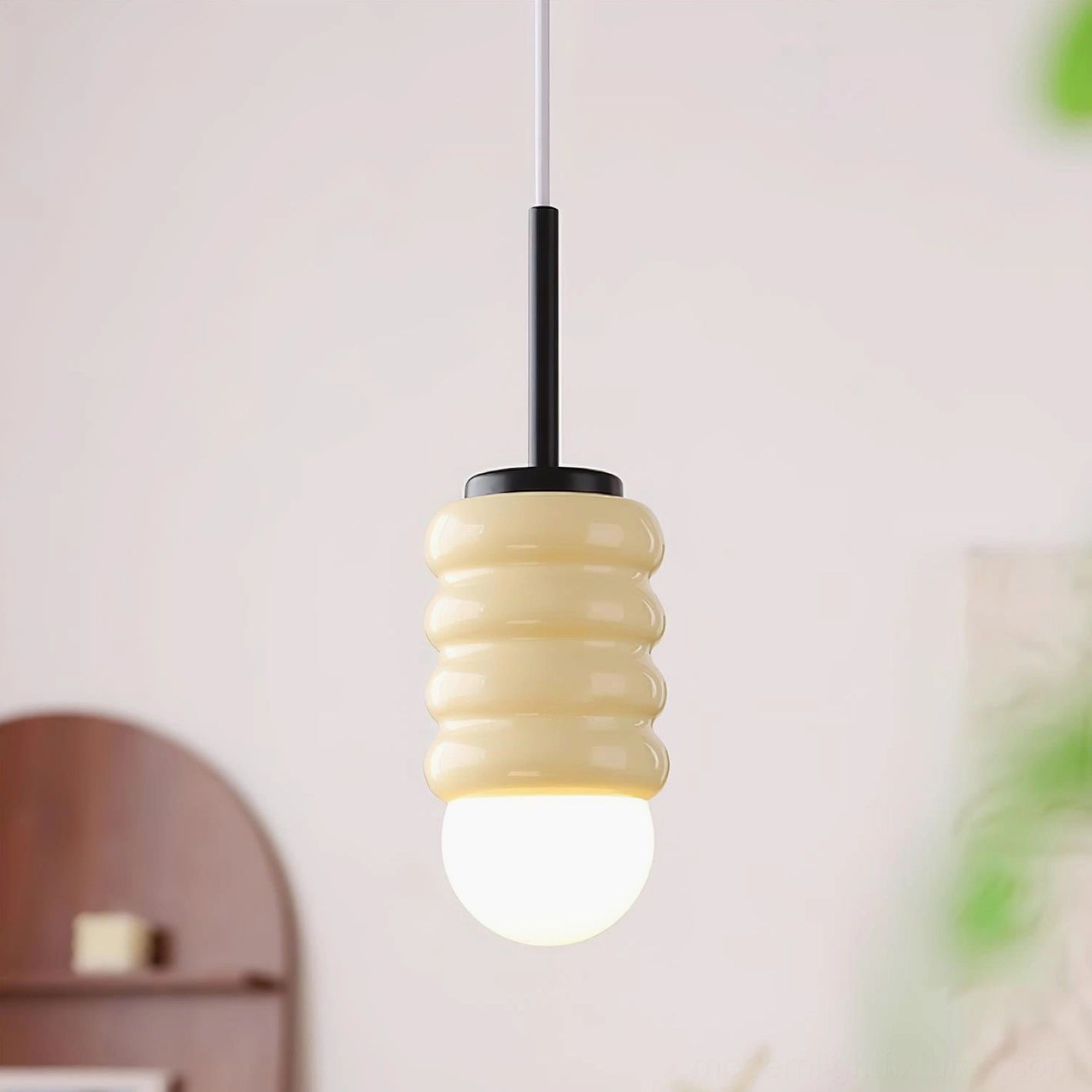 Modern ceramic pendant light in cream with black metal top, displayed in vintage bedroom setting with warm glow