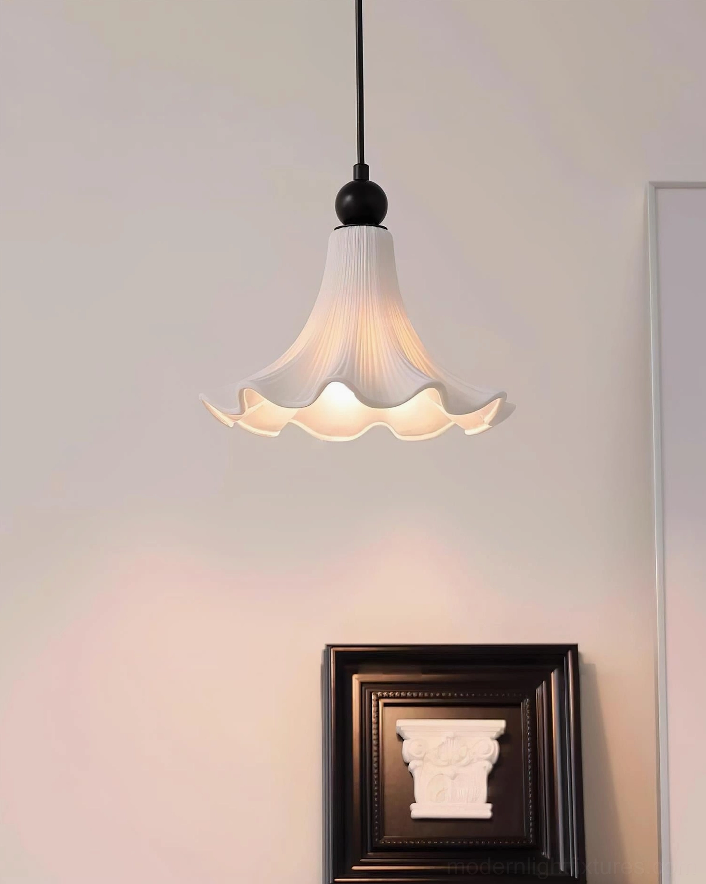 Florin Ripple pleated flower pendant light with black metal fixture positioned above decorative wall frame in home corner setting