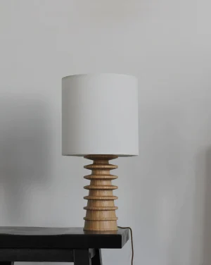 Rivaro modern table lamp three-quarter view showing sculptural wooden base design and cylindrical shade