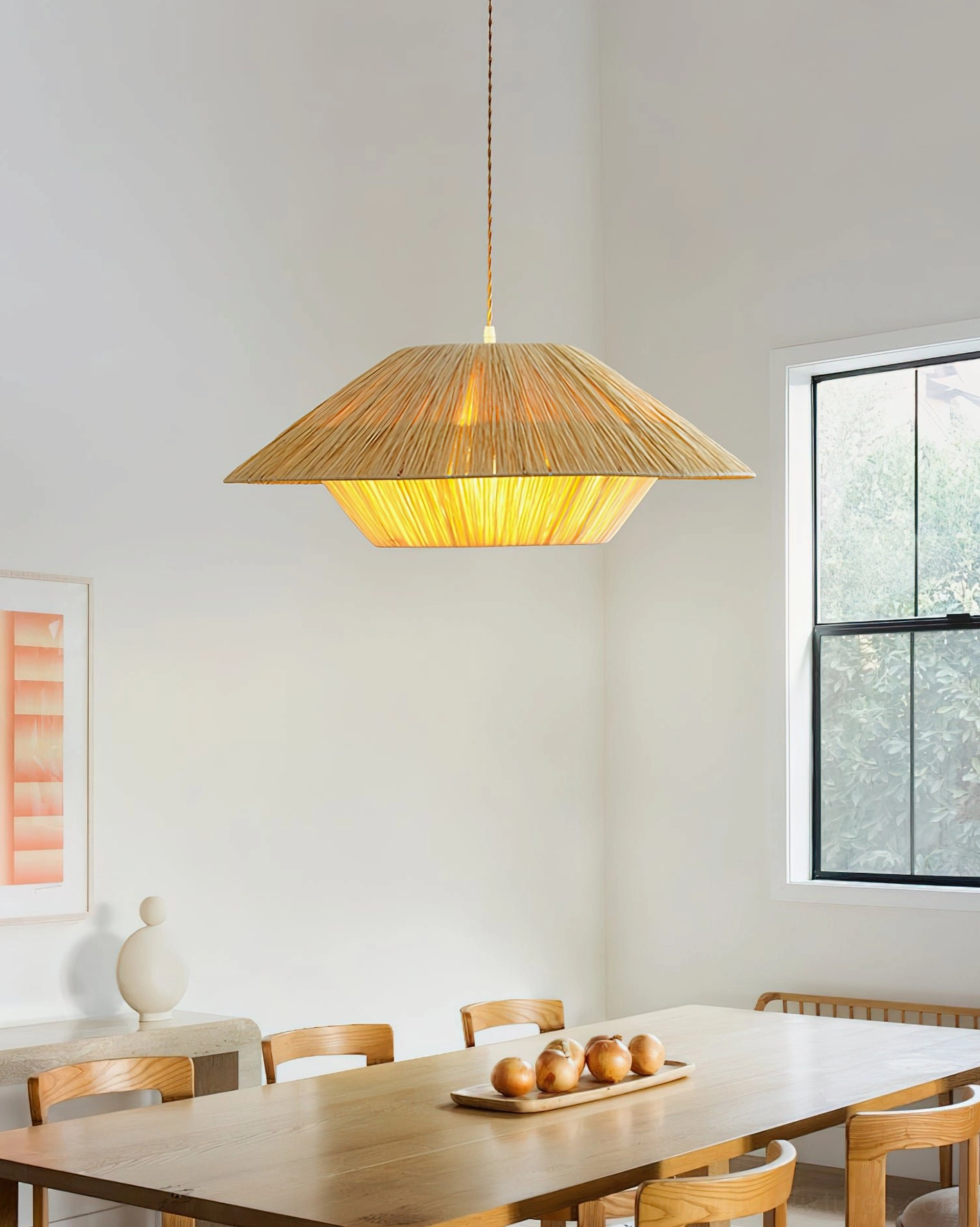 Rivora woven pendant light hanging above wooden dining table in boho farmhouse style dining room