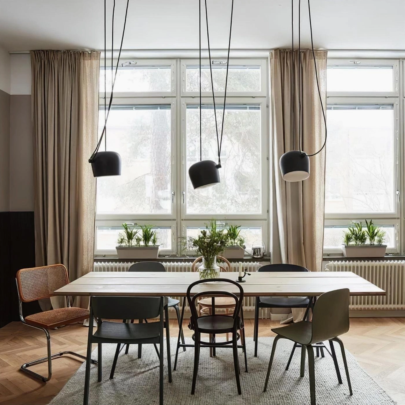 Mixed multi-drop Ronan pendant lights with black and white cylinder shades in bright dining room with windows