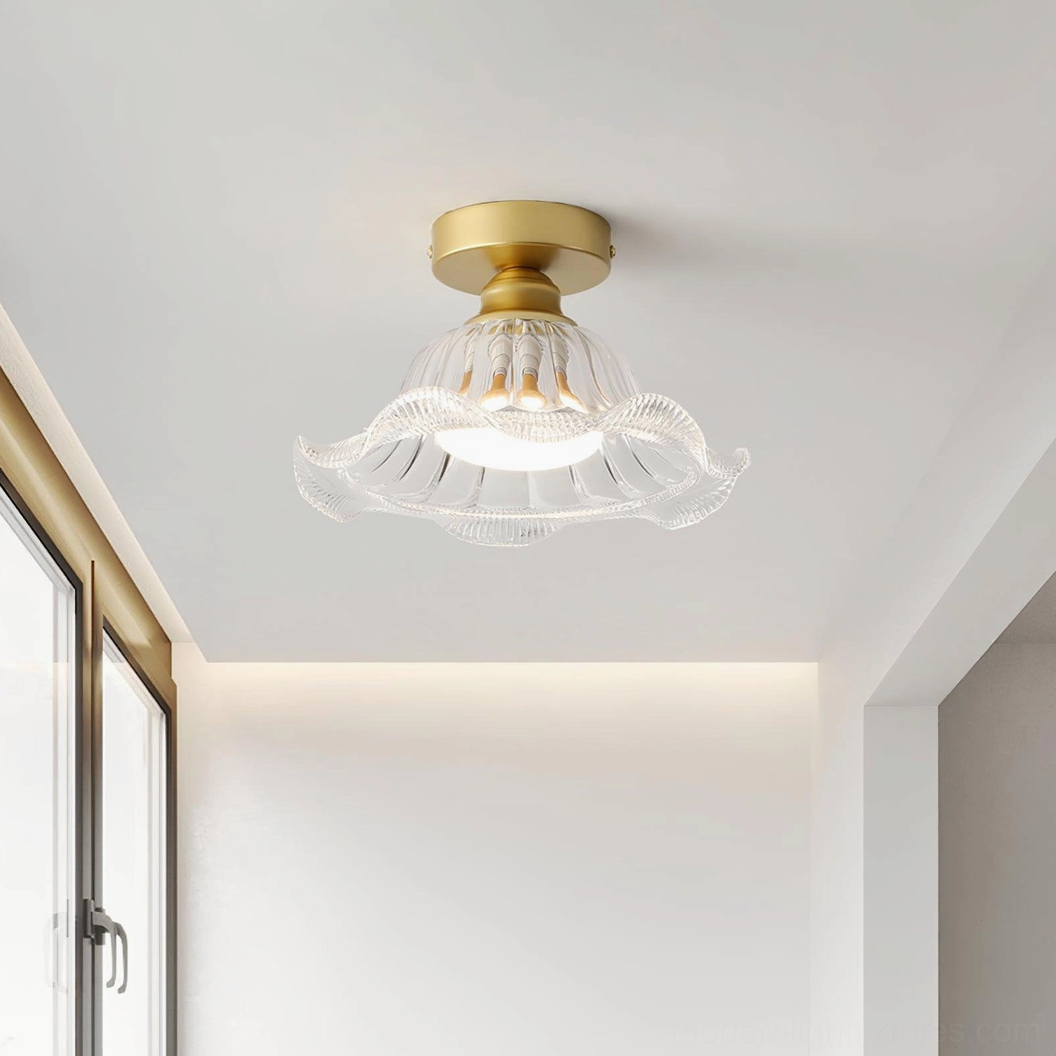 Rosa brass and glass ceiling fixture mounted on white wall in minimalist entryway, eye-level perspective