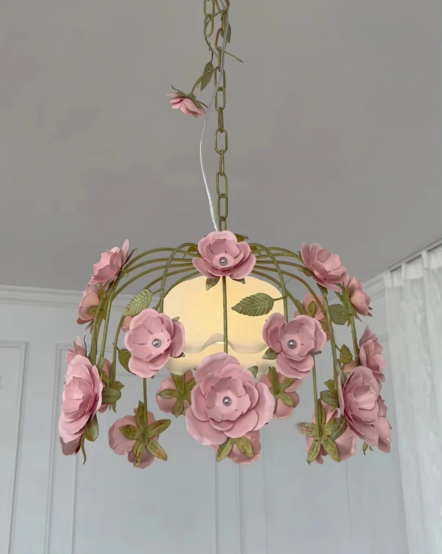 Rose pendant chandelier with gem-set pink blooms, green chain and metal frame, indoor window setting with romantic ambiance
