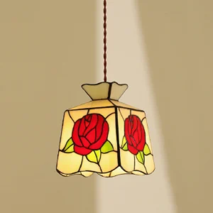 Stained glass rose pendant lamp illuminated in warm indoor setting showing cream and red glass with black lead lines
