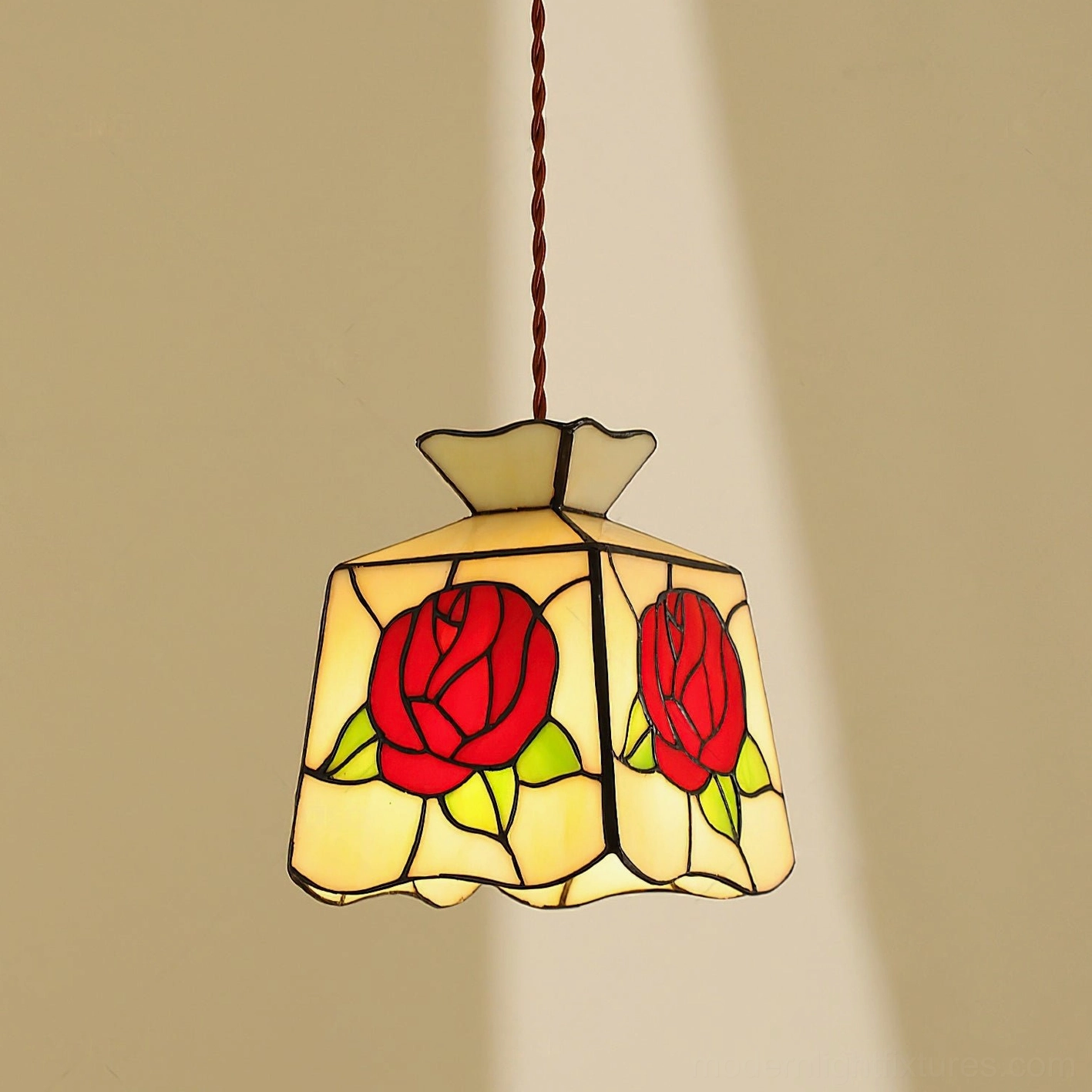 Stained glass rose pendant lamp illuminated in warm indoor setting showing cream and red glass with black lead lines