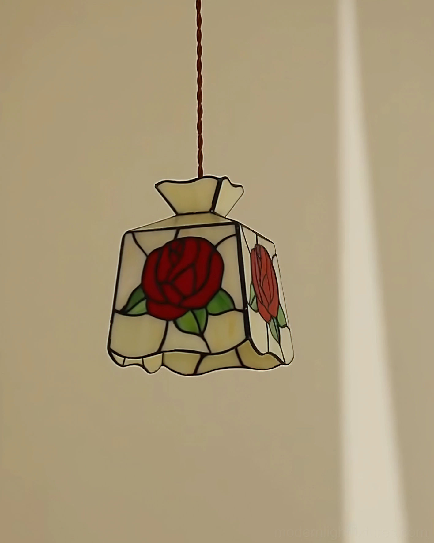 Cream and black stained glass rose pendant lamp with detailed lead trimming against warm wall backdrop