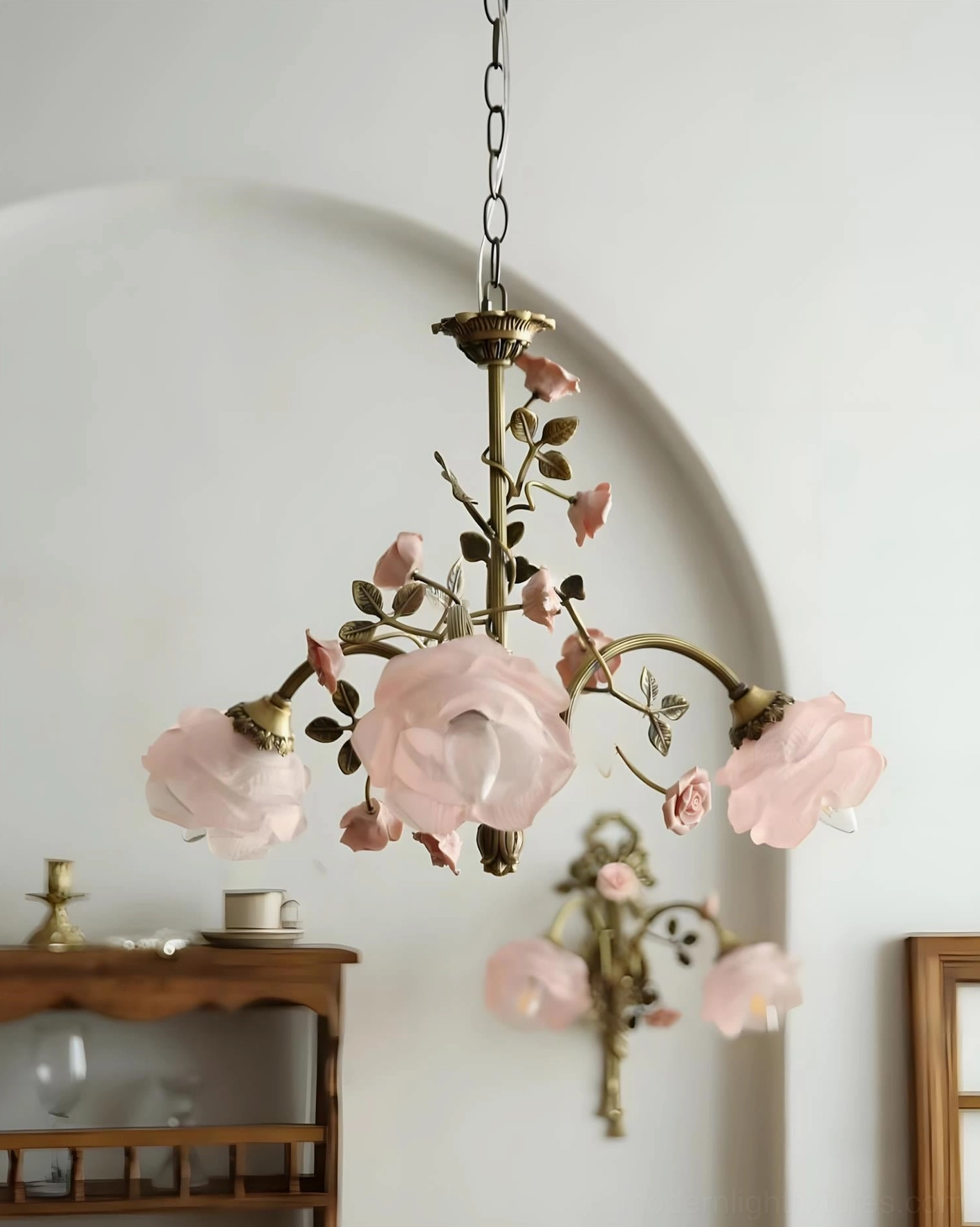 Delicate rose vine detailed glass shades on floral chandelier with antique brass frame showing handcrafted botanical character