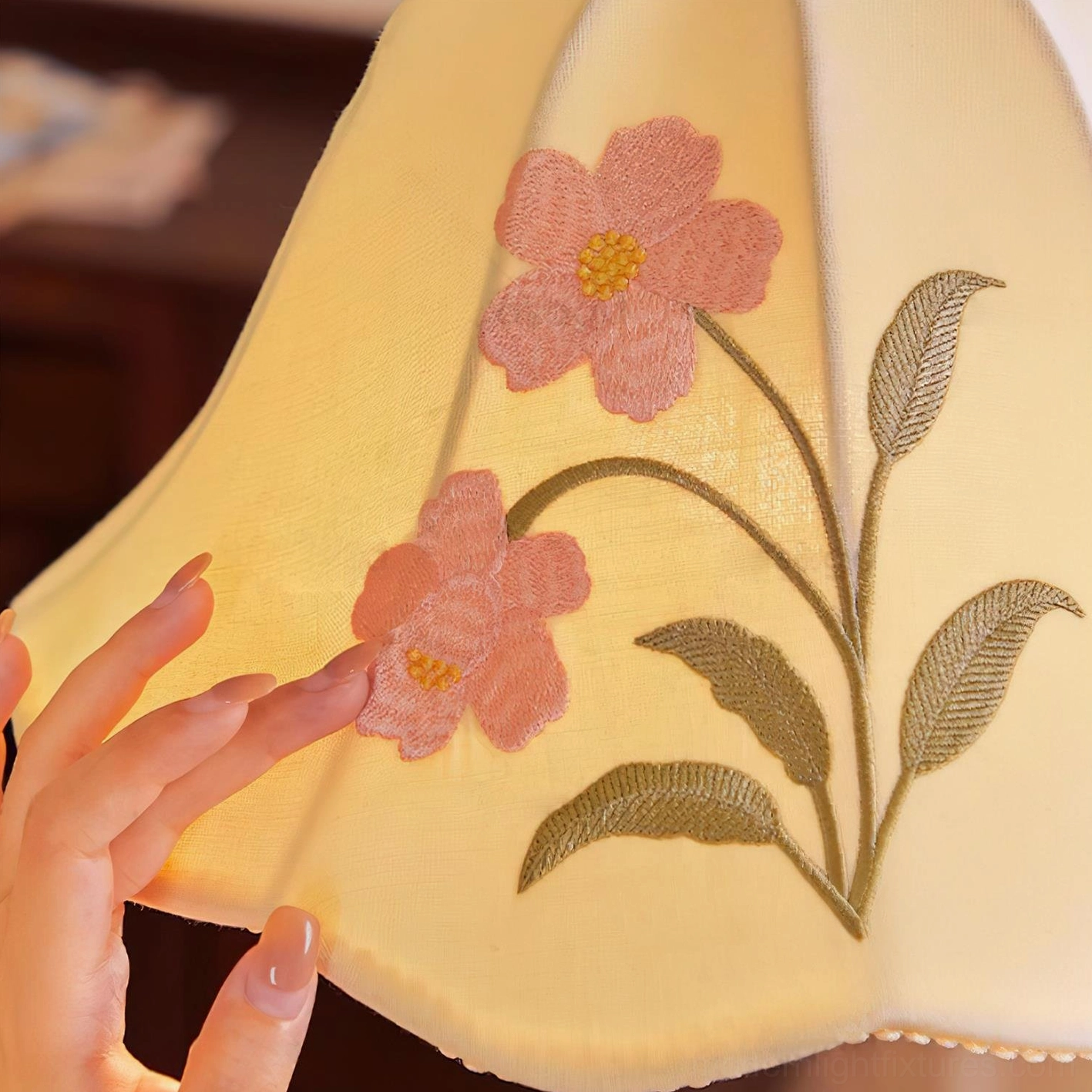 Close-up of Roselle pendant lamp shade embroidery showing pink flowers and green leaf details on fabric with wavy edge