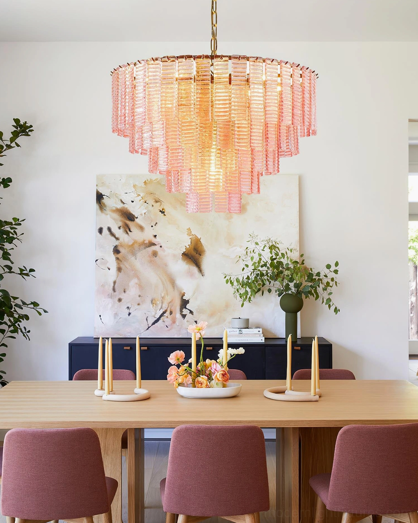 Rosewater tiered chandelier hanging in residential dining room - warm glowing pink glass over burgundy dining chairs, modern pendant lighting design