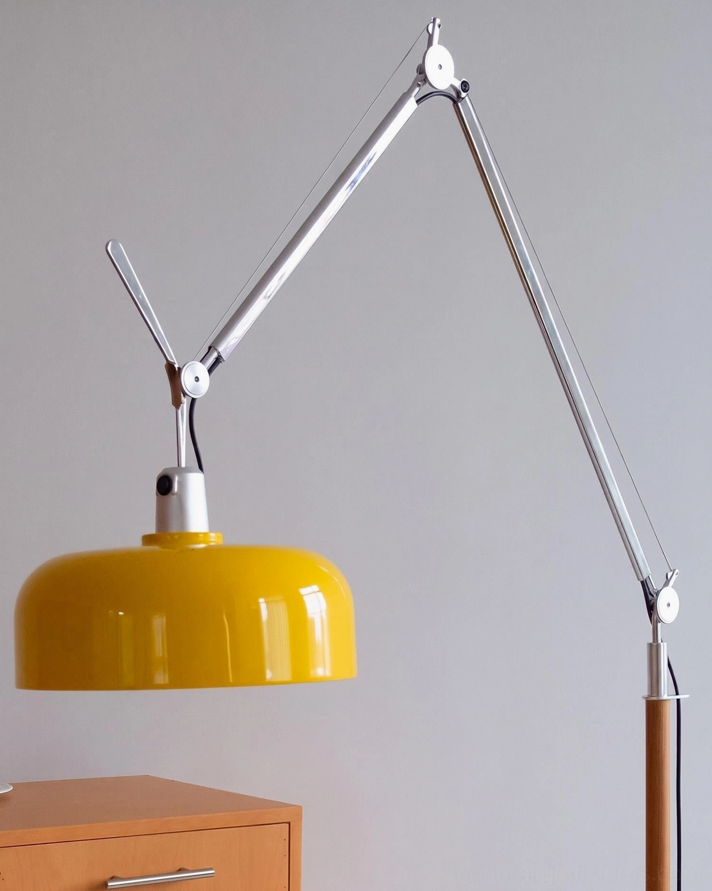 Rosso floor lamp close-up detail with yellow dome shade showing aluminum joints, arm, and partial ash wood pole