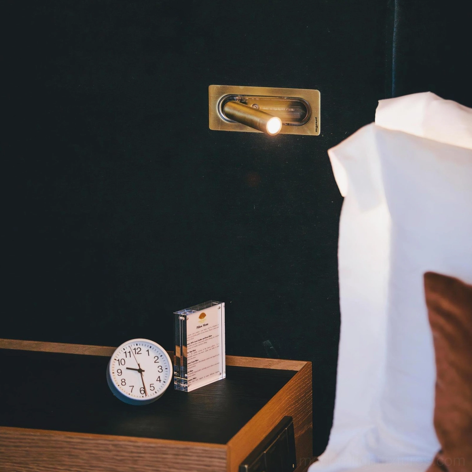 Bedroom reading setup featuring 360-degree rotatable wall lamp adjusted for comfortable nighttime reading angle
