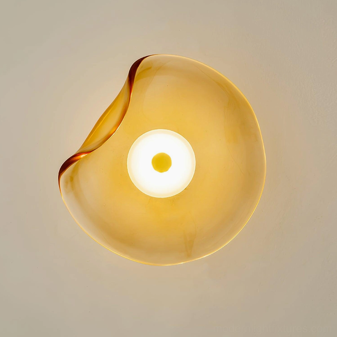 Round Nebulae amber glass wall light fixture - front close-up view showing translucent glass material with warm glow