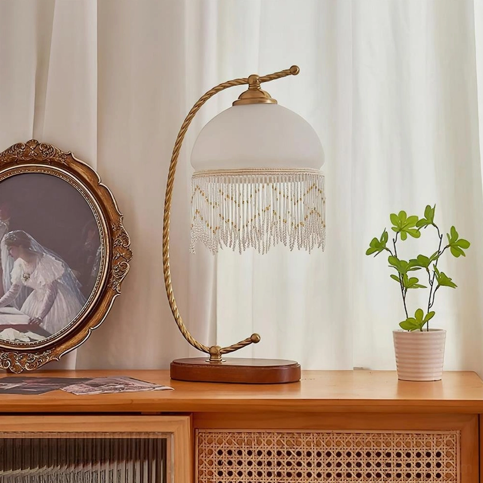 Roussillon Tassel Table Lamp with white frosted glass shade beaded tassel on vintage dresser with potted plant and mirror