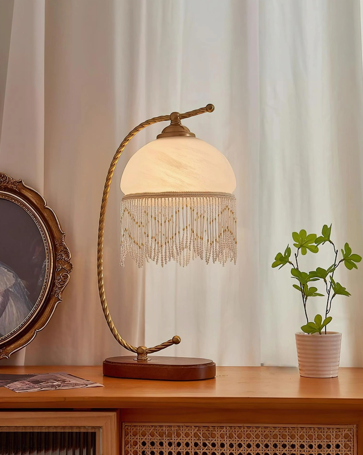 Roussillon Tassel Table Lamp off-white frosted glass shade front view vintage dresser with potted plant and decorative mirror