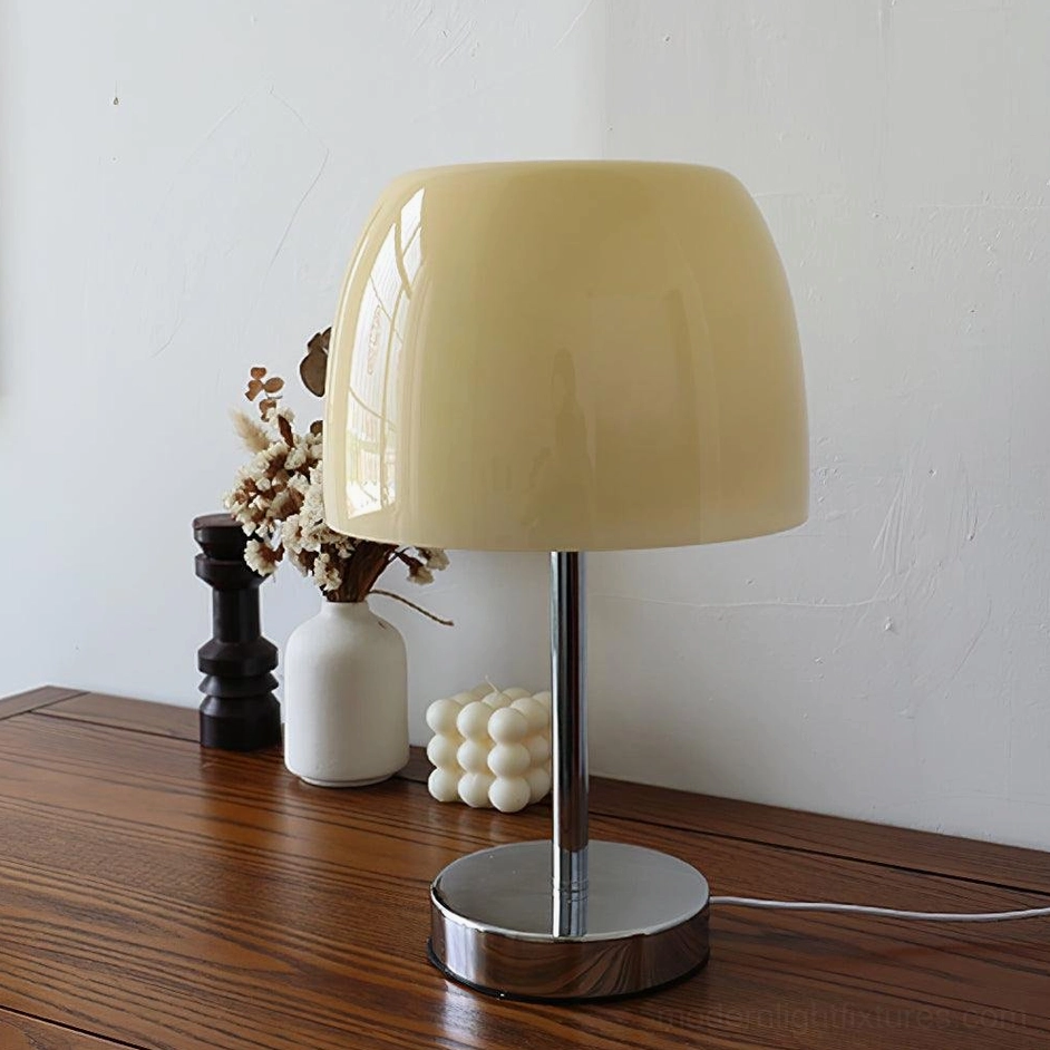 Modern glass table lamp with cream shade on wooden desk with dried flowers and home decor