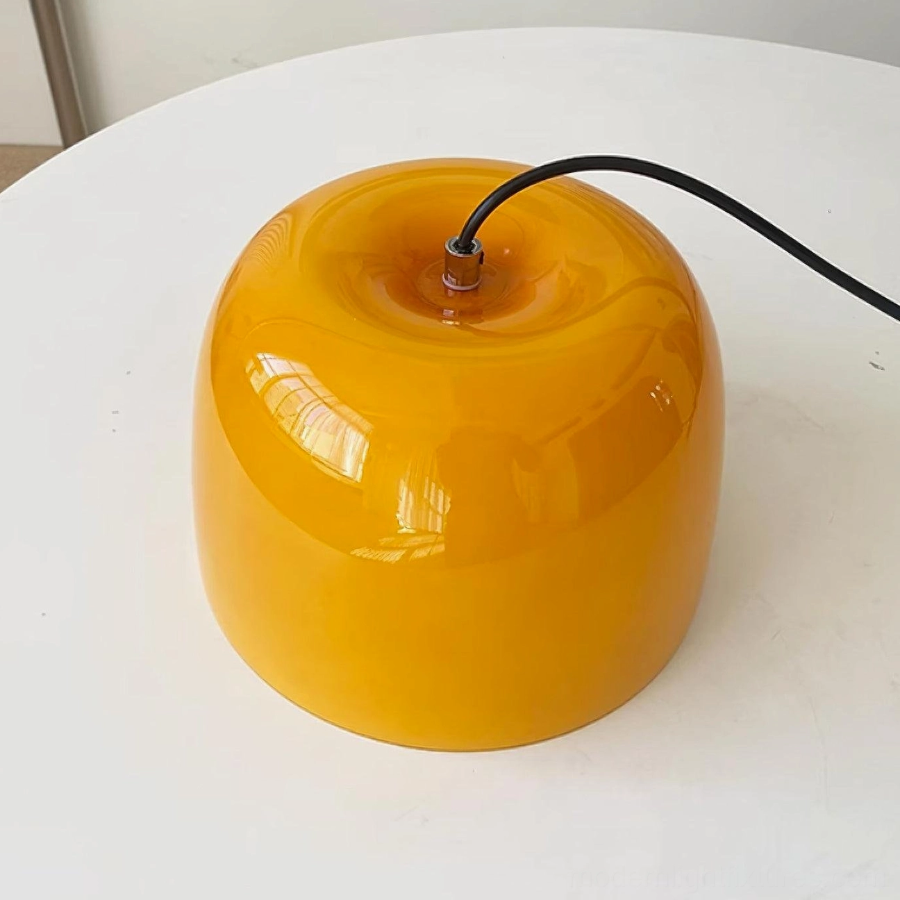 Roxboro pendant lamp demonstrating sleek metal frame and glossy amber glass shade combination