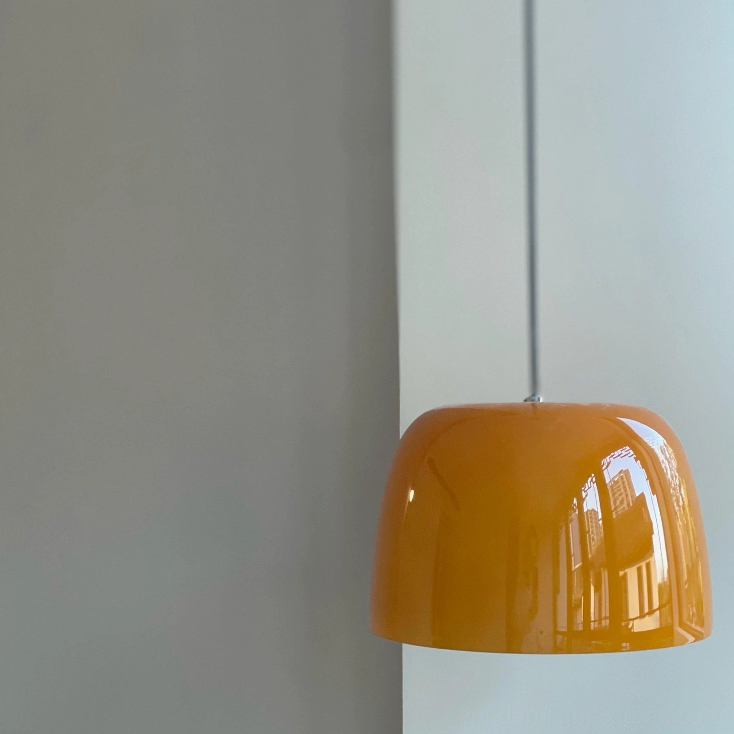 Low-angle side view of Roxboro pendant light showing light reflection on smooth amber glass shade
