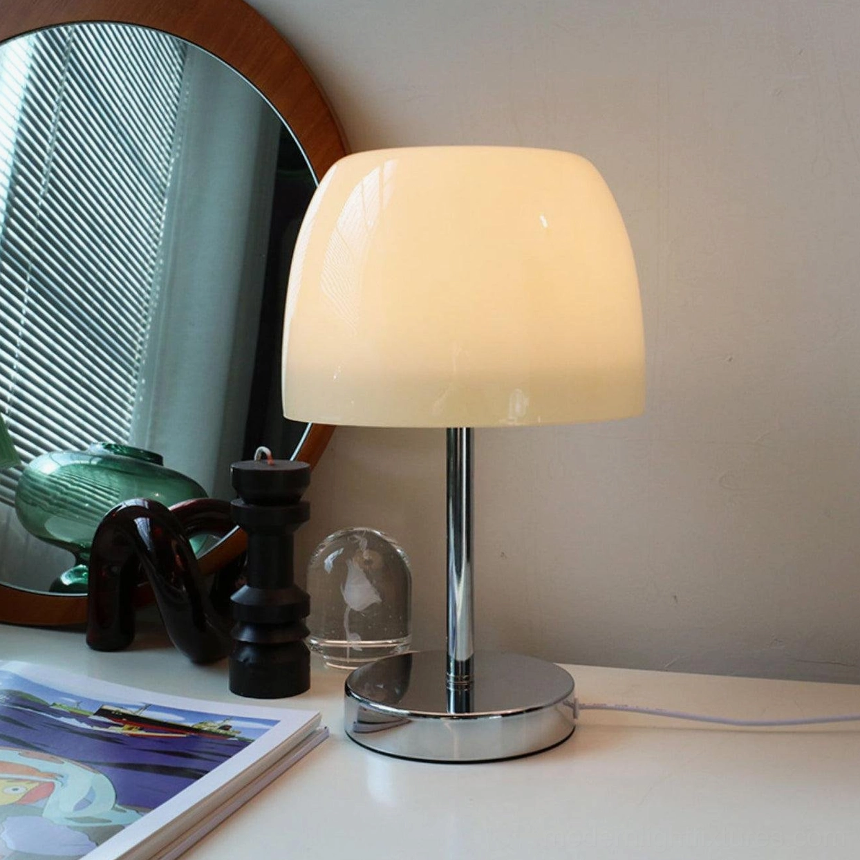 Modern table lamp with white shade on dresser paired with mirror and home accessories