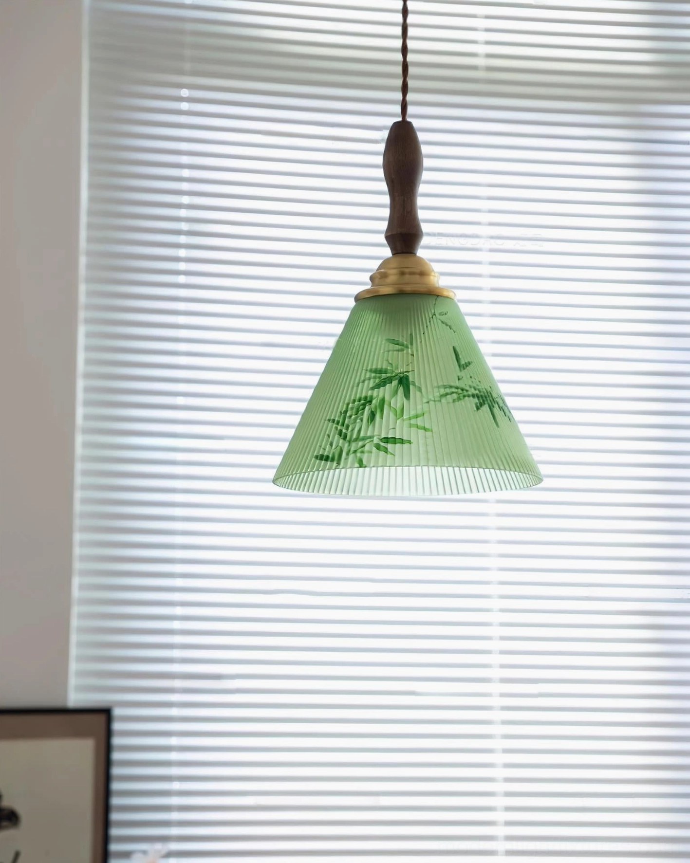 Botanical pendant lamp front low view showing tapered green shade with intricate bamboo design