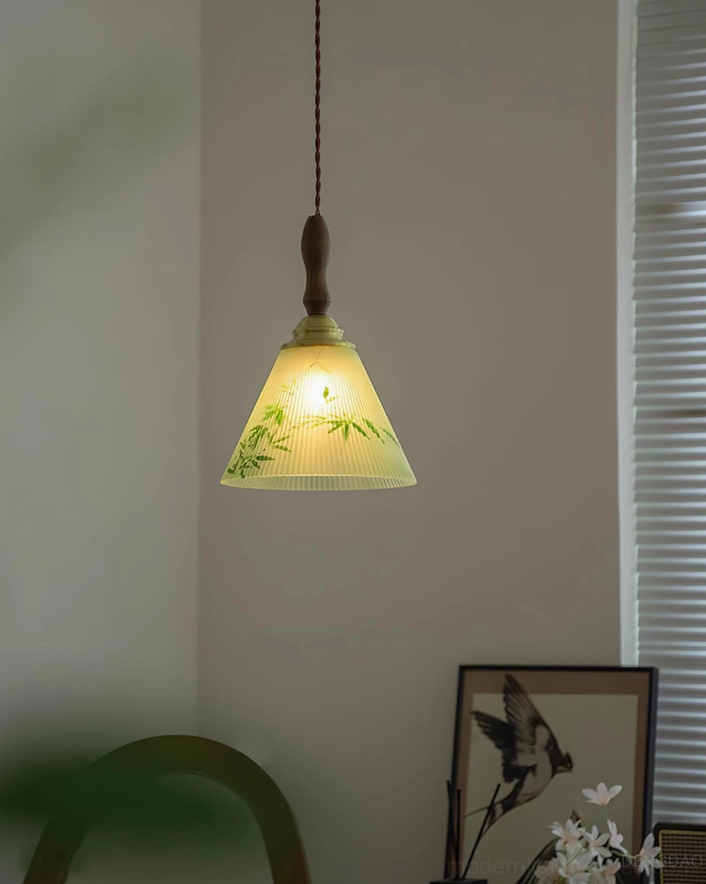 Illuminated botanical pendant lamp emitting warm yellow glow in residential corner with wall art