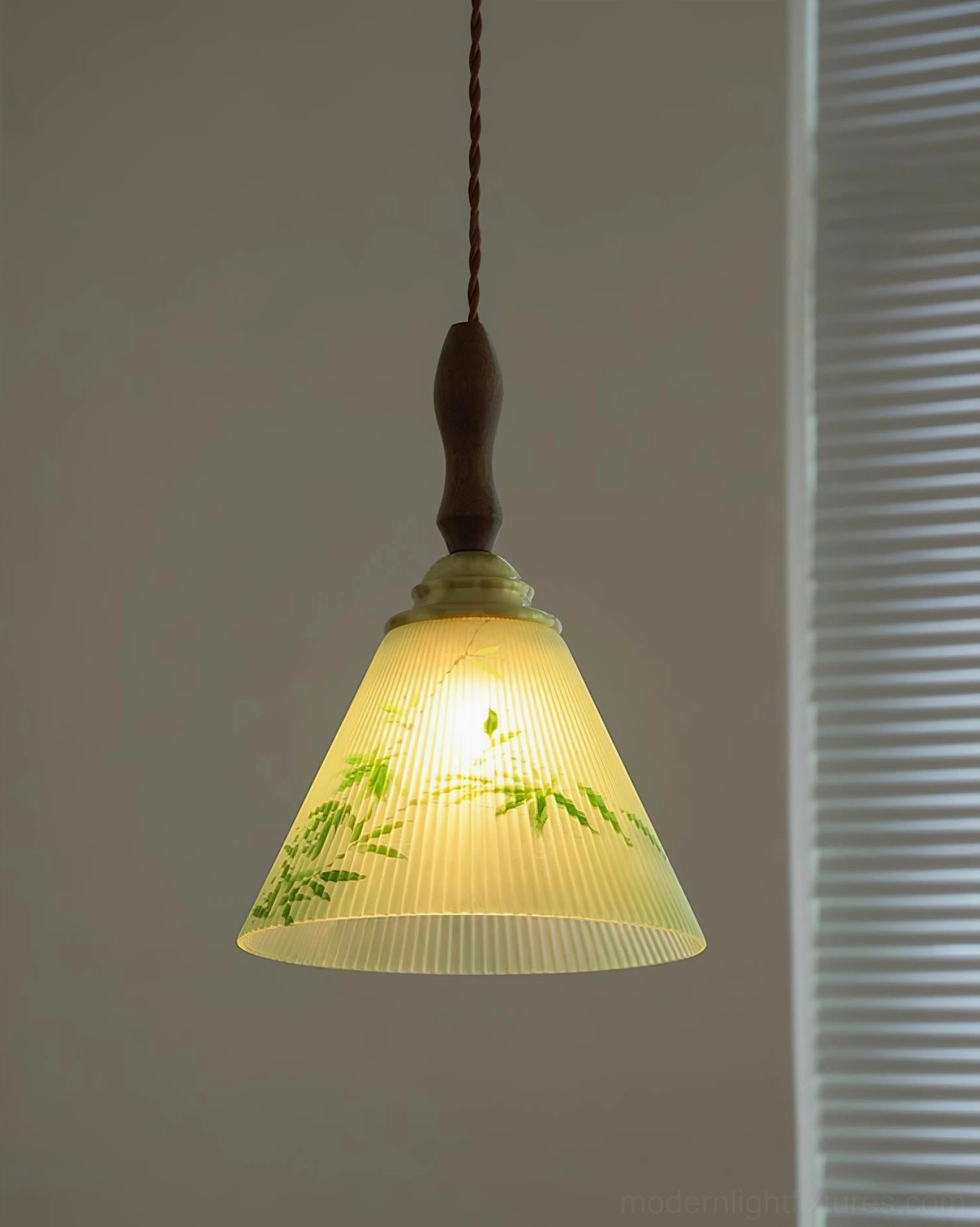 Powered-on botanical pendant light casting warm ambient glow against wall with louver trim