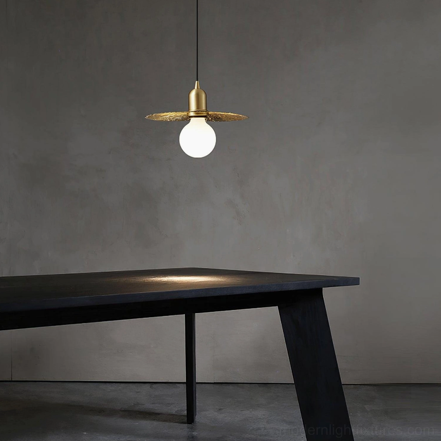 Rozeta brass pendant fixture with flat petal shade casting warm ambient light in minimalist workspace
