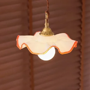 Close-up low-angle view of ruffled glass pendant light showing exposed warm glowing bulb and brass hardware details