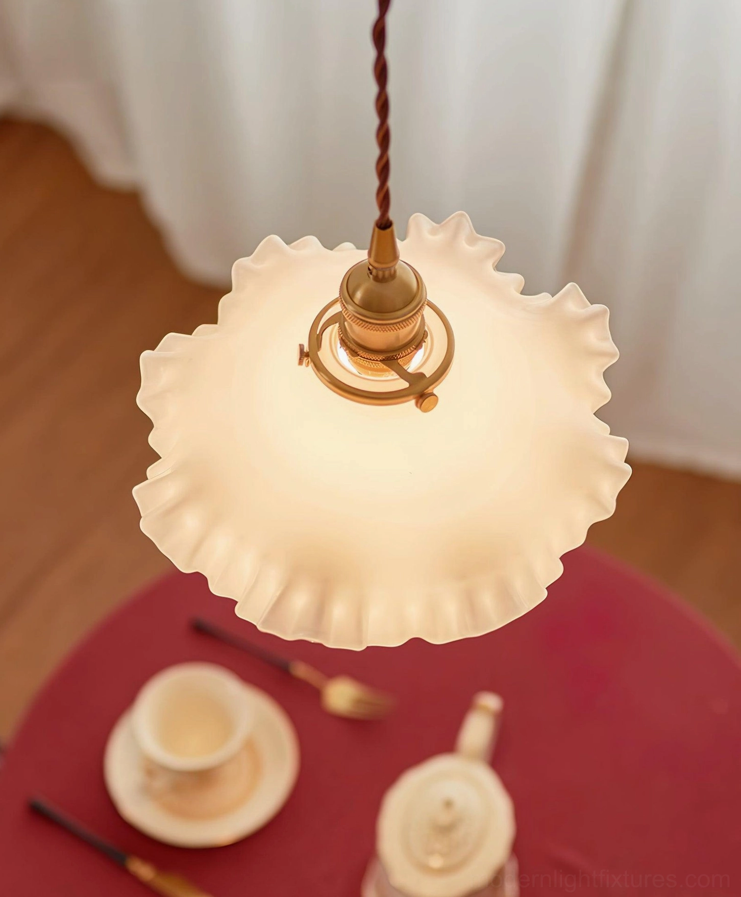 Ruffled glass pendant light photographed from below, showing translucent shade and visible brass fixture structure
