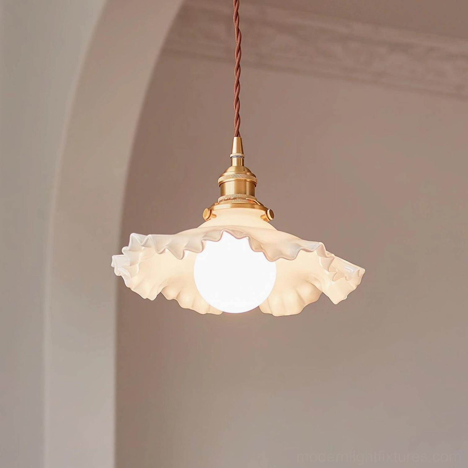 Ruffled glass pendant light with warm brass hardware and glowing bulb, eye-level view in indoor space with arched doorway
