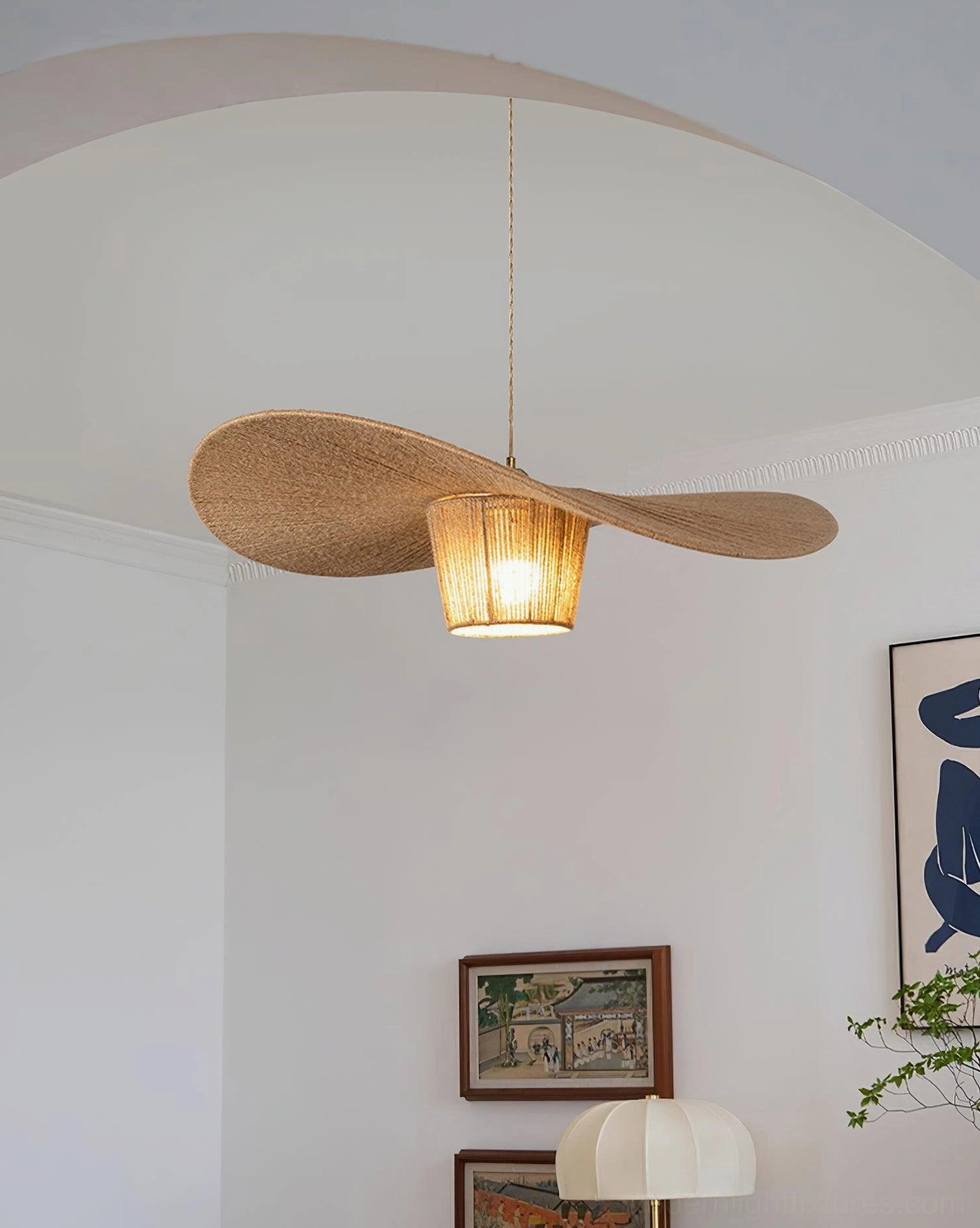 Petal-shaped hemp rope pendant lamp illuminating minimalist living room with wall art and warm atmospheric glow