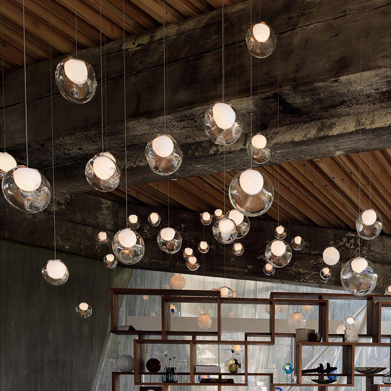 Clear glass globe cluster chandelier with warm ambient lighting in rustic restaurant interior with wooden beams, industrial modern style