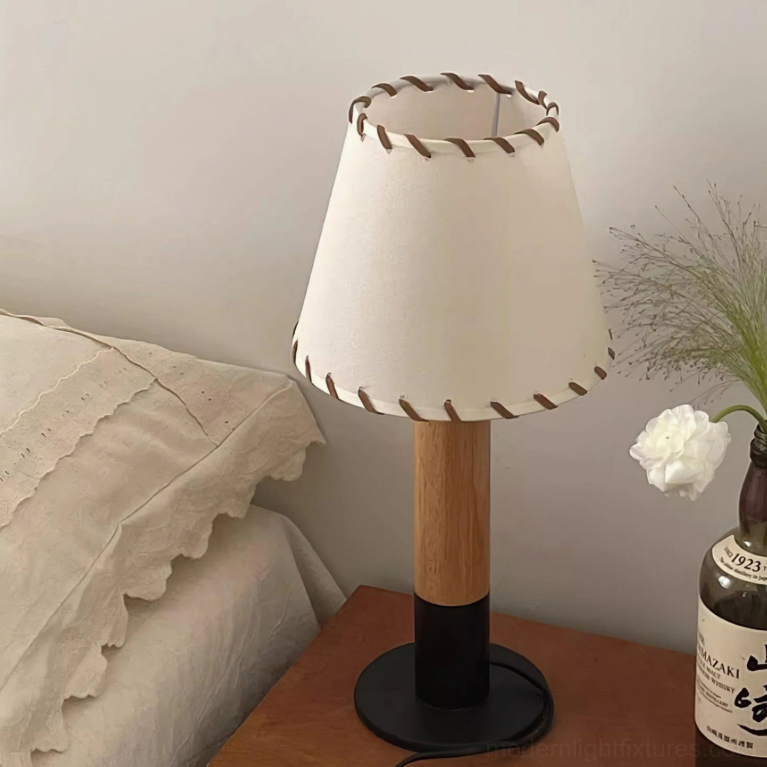 Low angle view of rustic table lamp with black metal base and hand-stitched fabric shade bedside setting