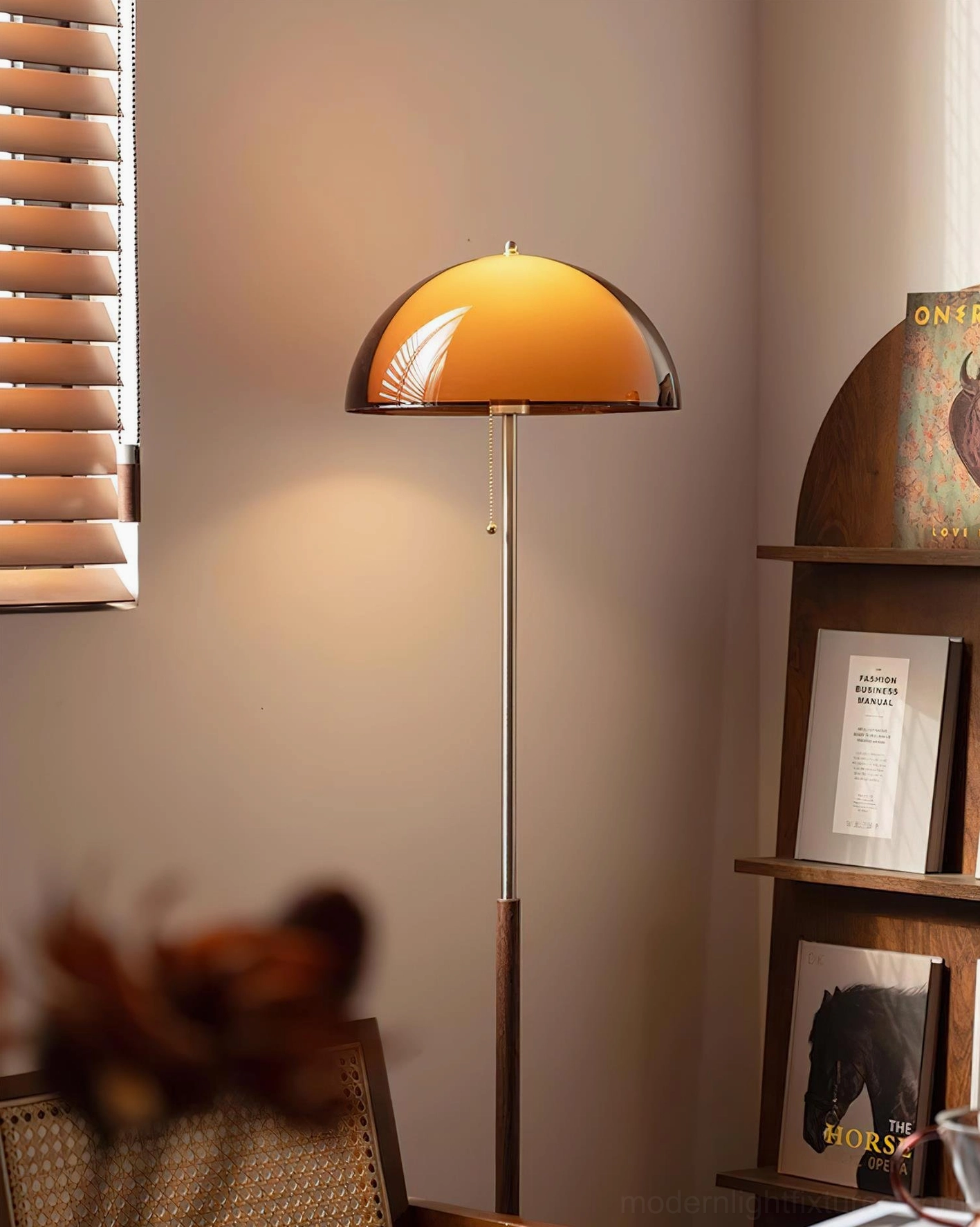 Rustina dome floor lamp with warm amber shade and silver metal pole in bookshelf display corner, low front angle view
