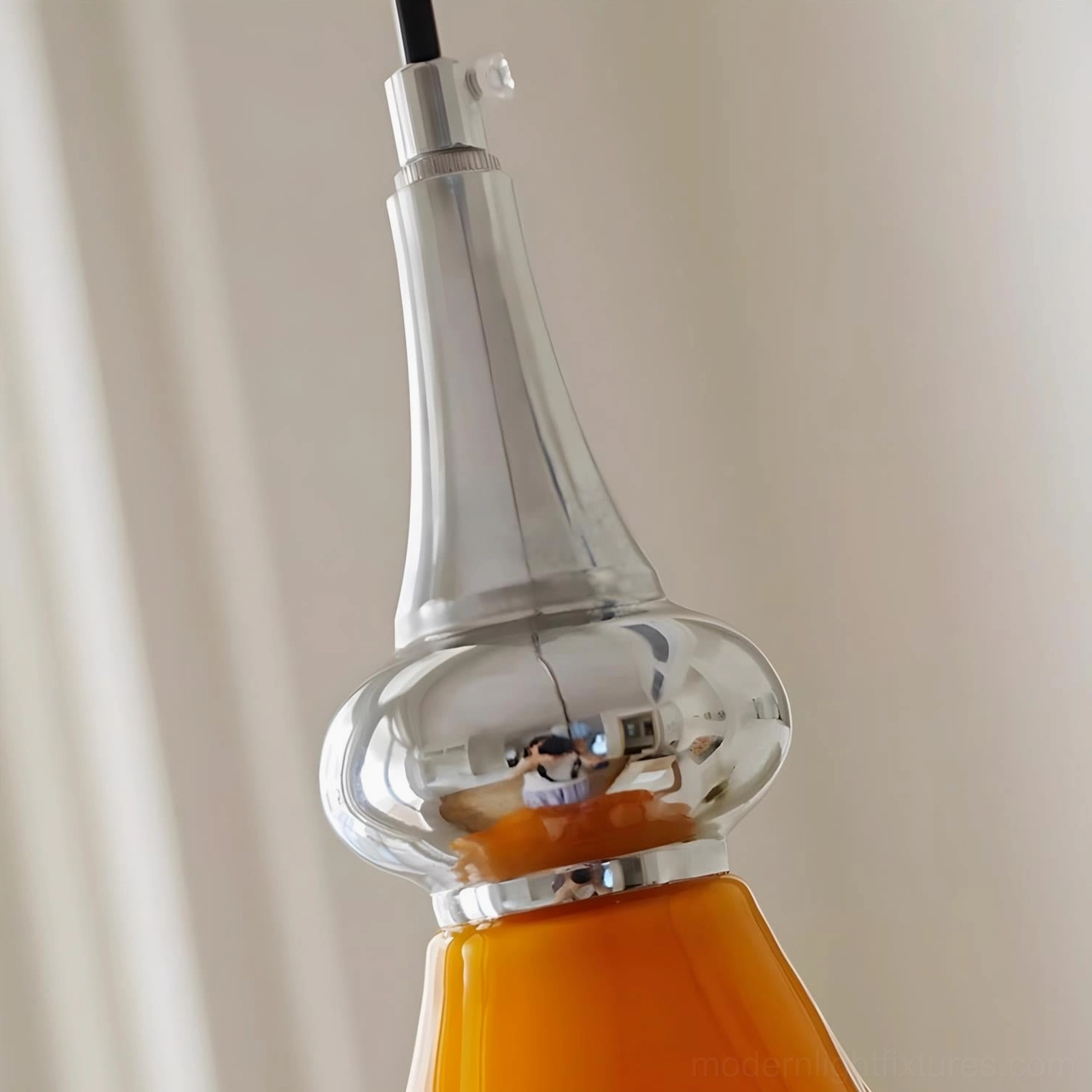 Saffron flower pendant light hardware detail showing polished chrome metal finish attached to orange glass shade from below