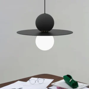 Modern black disc pendant light with glowing white sphere in contemporary home office setting