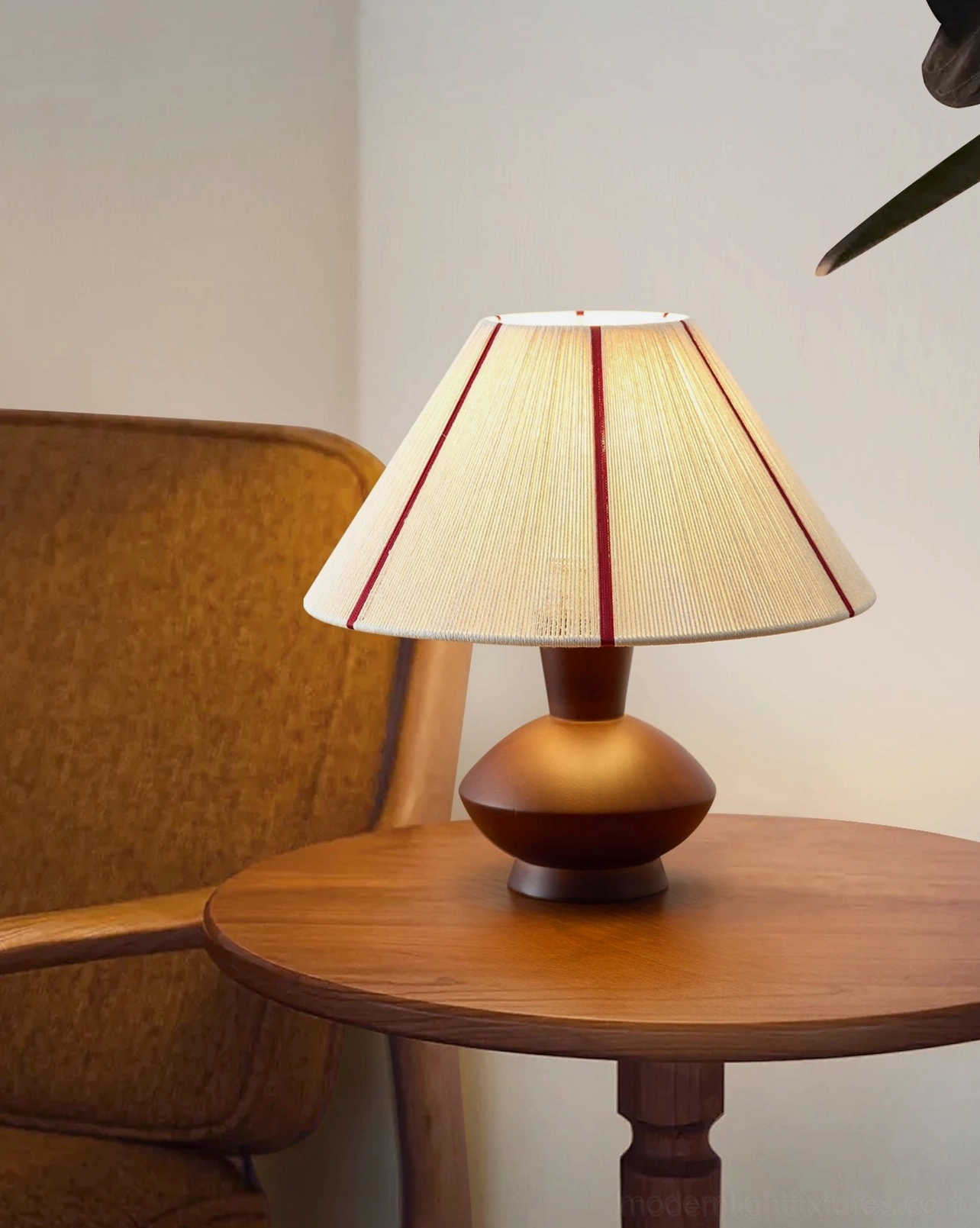 Sandia table lamp on round wooden side table next to upholstered armchair, living room corner setting, warm interior design styling