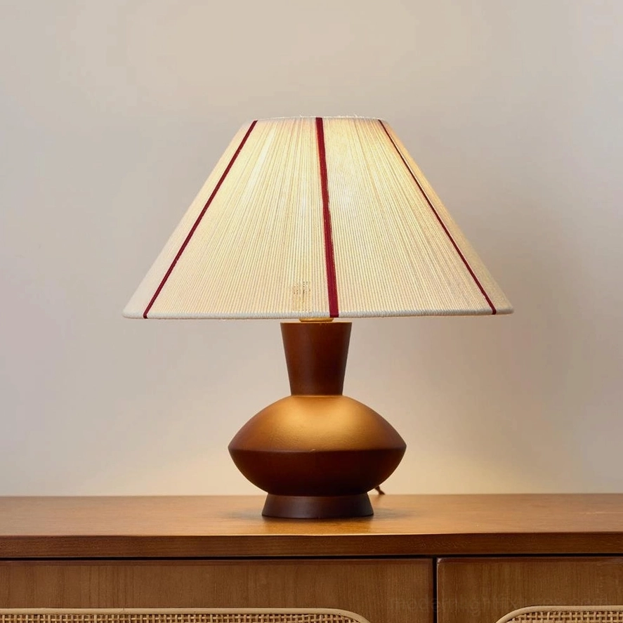 Sandia table lamp on wooden console table, hand-woven beige shade with red stripe detailing, warm chestnut brown walnut base, interior styling