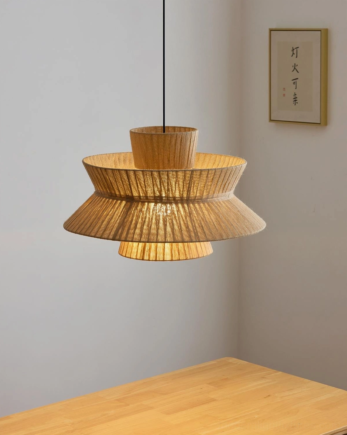 Tiered woven jute pendant lamp hanging above wooden dining table in warm minimalist boho interior setting
