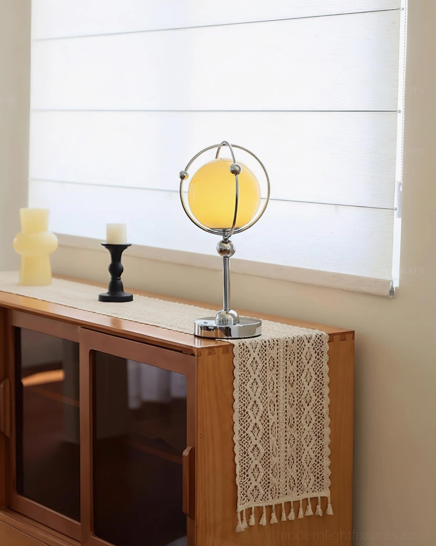 Saturn Hoop Table Lamp styled on wooden console table with candle holders and window blinds background