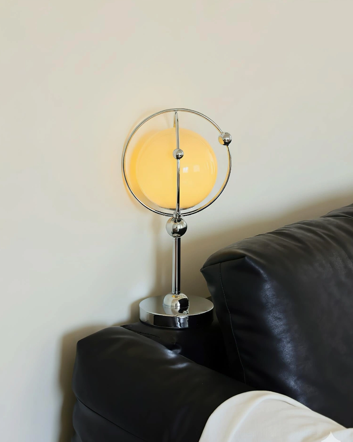 Saturn Hoop Table Lamp with warm yellow illumination on black leather sofa side table accent lighting