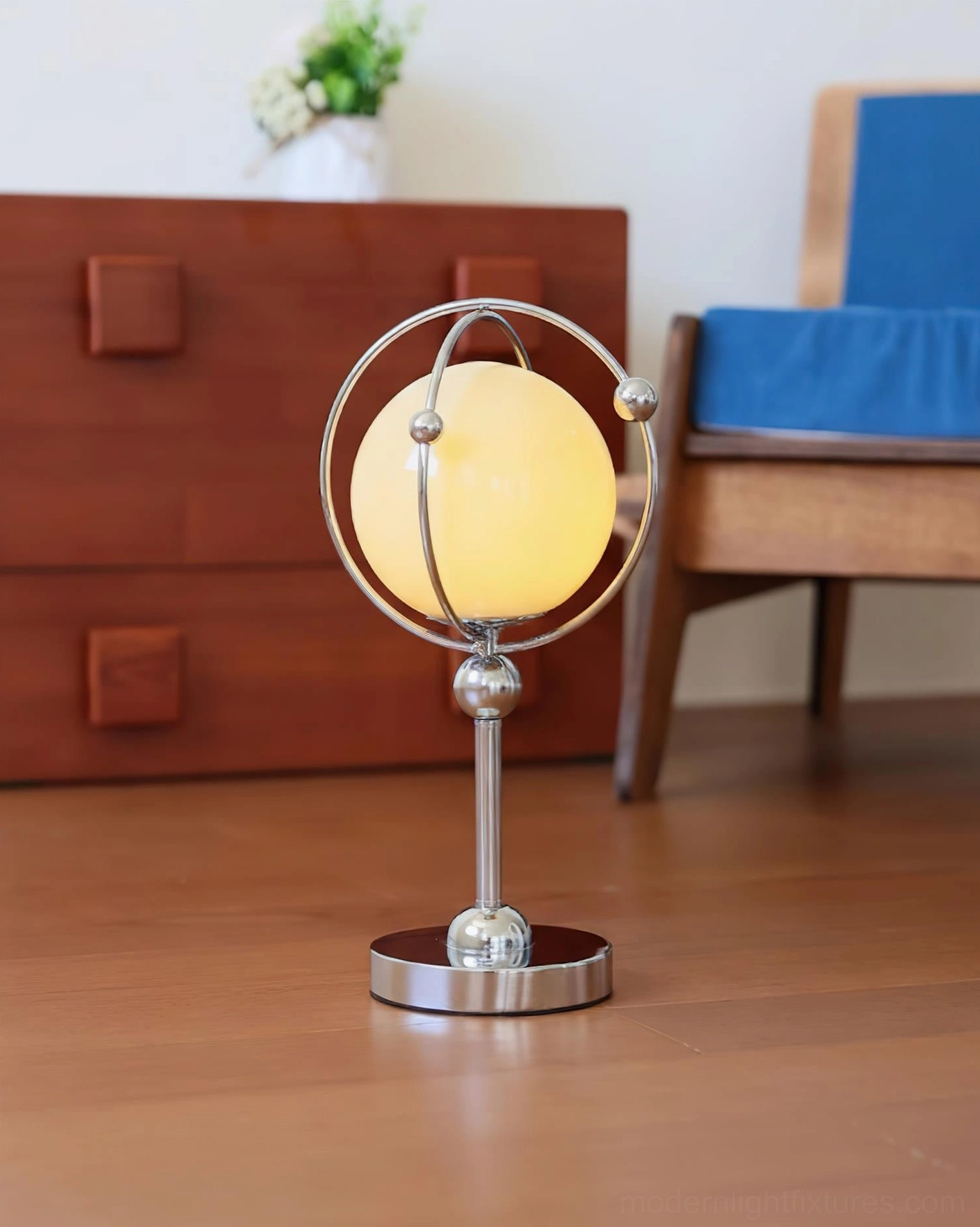 Modern Saturn Hoop Table Lamp on wooden cabinet in living room setting with blue upholstered chair