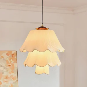 Savena two-tier pleated pendant lamp with layered cream fabric shade in vintage cottage living room setting with floral wall art