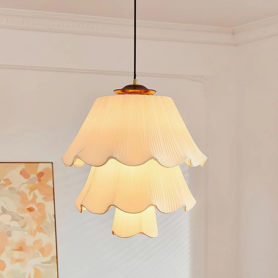 Savena two-tier pleated pendant lamp with layered cream fabric shade in vintage cottage living room setting with floral wall art