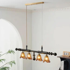 Savoy pendant chandelier installed in minimalist dining room with brass ceiling mount and four amber glass lamp heads over dining table