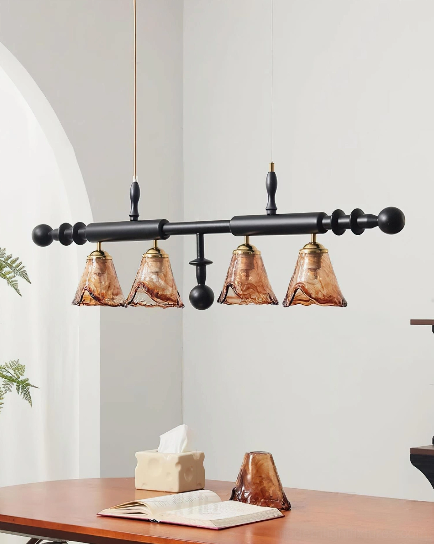 Savoy 4-light linear pendant chandelier side perspective with spherical black metal decorative accents above wooden table