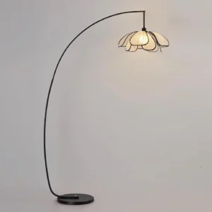 Savoy floor lamp three-quarter front view showing curved metal pole, petal-shaped fabric shade, and weighted circular base on gray background