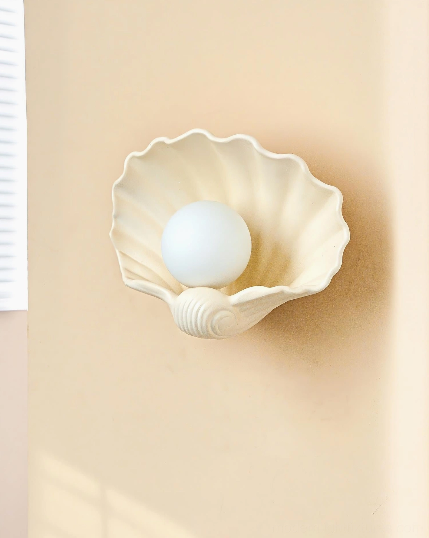 Scallop shell wall lamp close-up, sculptural ridged ceramic form, organic design detail, artistic light fixture